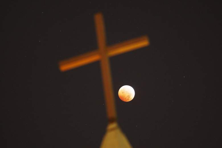 Una cruz religiosa iluminada durante un eclipse total en octubre de 2014. Algunos, como John Hagee, dicen que la cuarta luna de sangre es una profecía para el desastre y los tiempos finales.