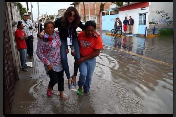 Lydia Cumming pide a vecinos que la carguen para no mojarse. 