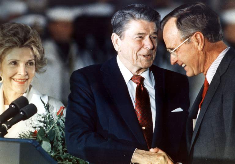 El presidente Ronald Reagan y el vicepresidente George Bush se dan la mano como primera dama Nancy Reagan mira en estado de 1991. (Getty)