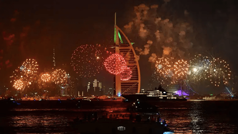 Las celebraciones de fuegos artificiales de Año Nuevo se ven sobre el horizonte de Dubai con el Burj Al Arab (R) y el Burj Khalifa (L), el edificio más alto del mundo, el 31 de diciembre de 2019.