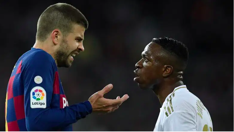 El defensor español del Barcelona Gerard Piqué (L) habla con el delantero brasileño del Real Madrid Vinicius Junior durante el partido de fútbol de la Liga española entre el Real Madrid y el Barcelona en el estadio Santiago Bernabeu en Madrid el 1 de marzo de 2020