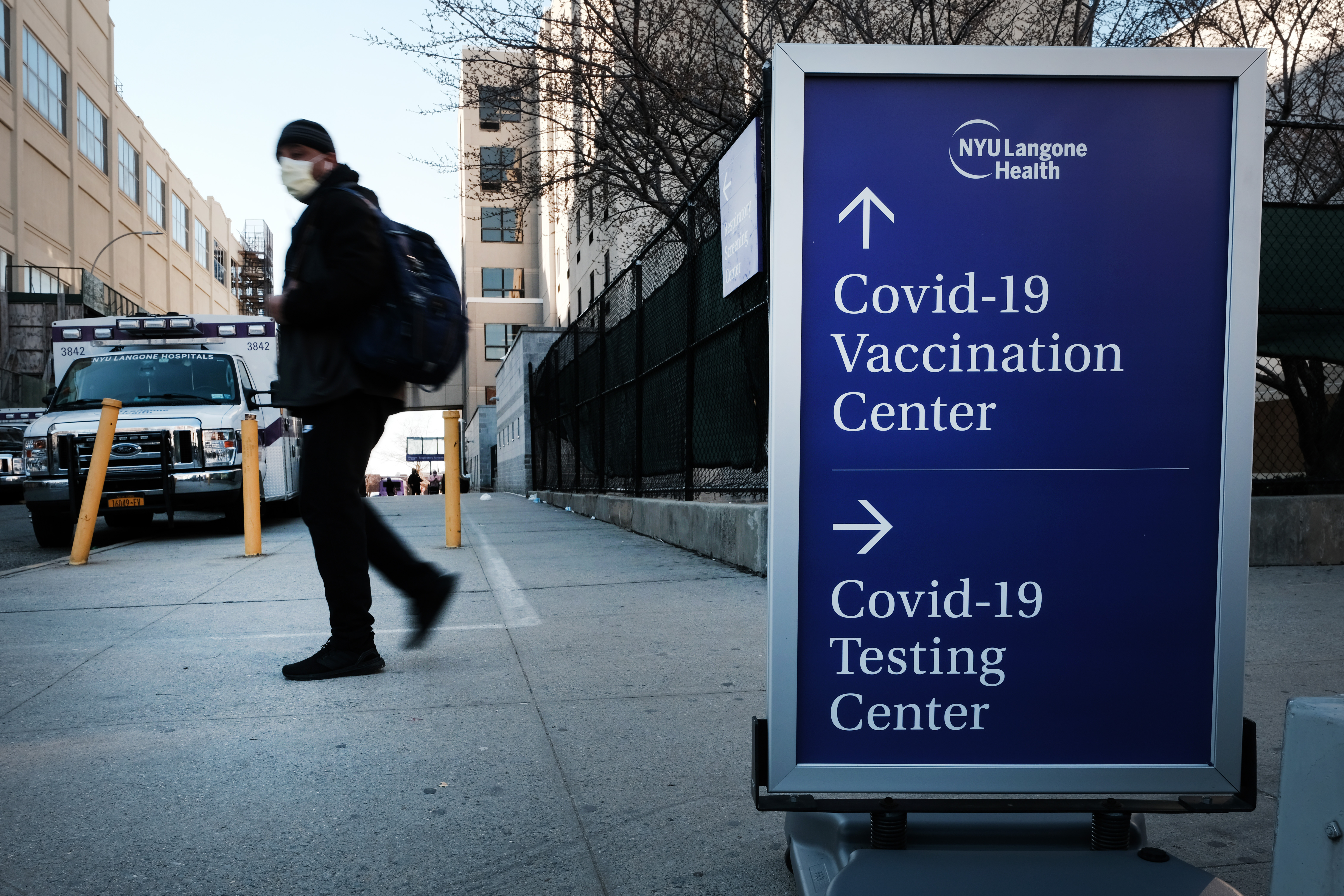 La gente camina junto a un letrero de una clínica de pruebas de Covid-19 y un lugar de vacunación de Covid fuera de un hospital de Brooklyn el 29 de marzo de 2021 en el distrito de Brooklyn de la ciudad de Nueva York.