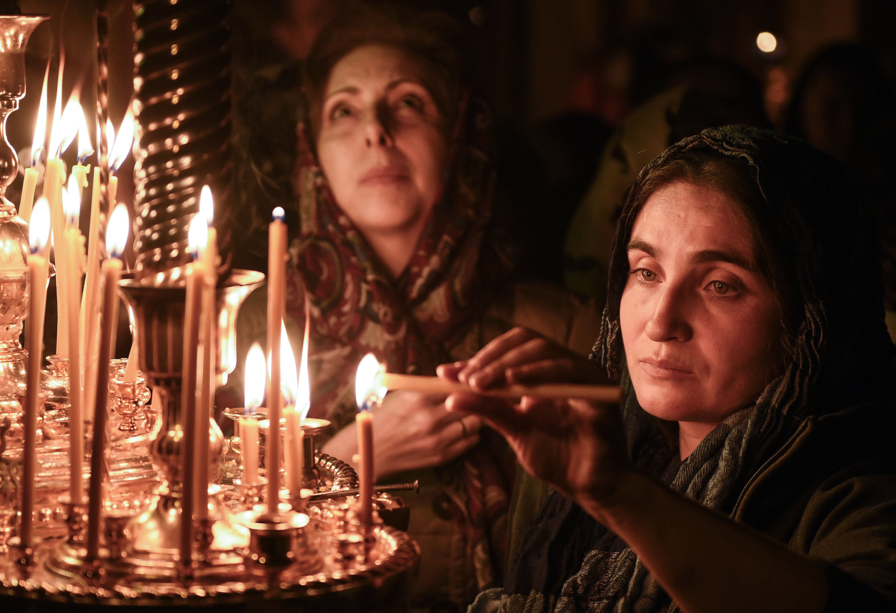 Mujeres encienden velas durante un servicio de Pascua en una iglesia en Bakú, a principios del 8 de abril de 2018.