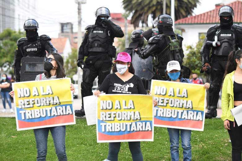 Mujeres sostienen carteles con la bandera colombiana que dicen "No a la reforma tributaria" durante una manifestación contra la reforma tributaria propuesta por el presidente colombiano Iván Duque, en Bogotá, el 28 de abril de 2021.