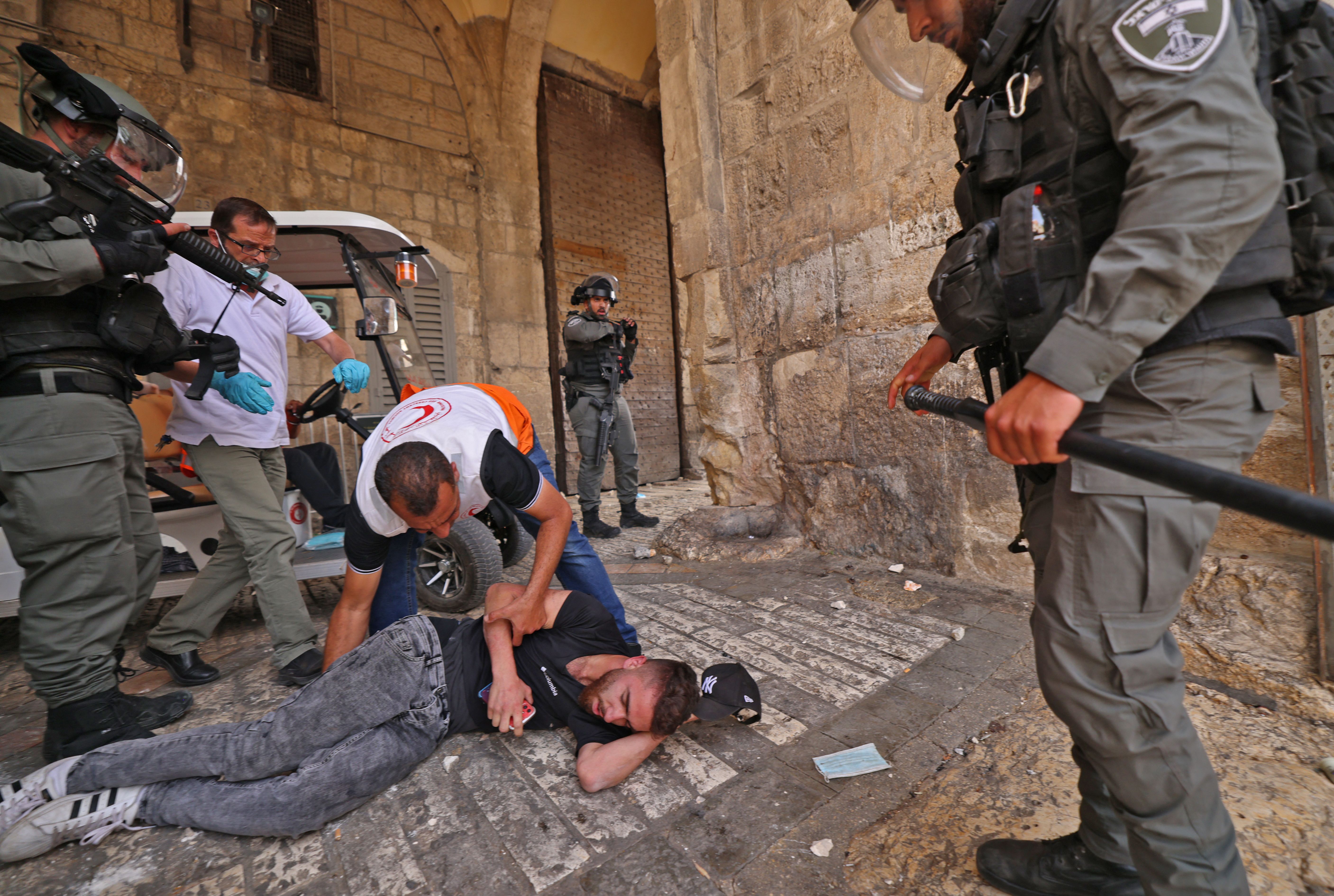 Los médicos palestinos ayudan a un manifestante herido en medio de enfrentamientos con las fuerzas de seguridad israelíes en la Ciudad Vieja de Jerusalén el 10 de mayo de 2021, antes de una marcha planificada para conmemorar la toma de posesión de Jerusalén por Israel en la Guerra de los Seis Días de 1967.