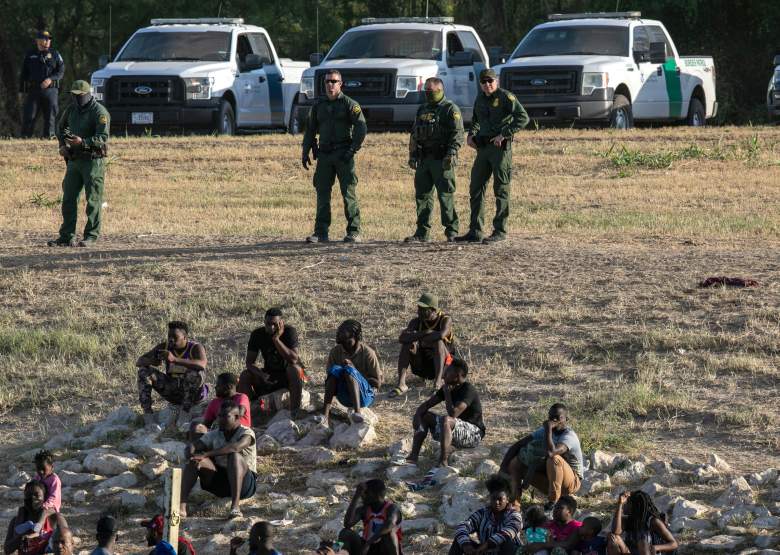 Agentes de la Patrulla Fronteriza de los Estados Unidos vigilan a los inmigrantes cerca de un campamento de migrantes en Del Rio, Texas, el 22 de septiembre de 2021, visto desde Ciudad Acuna, México.