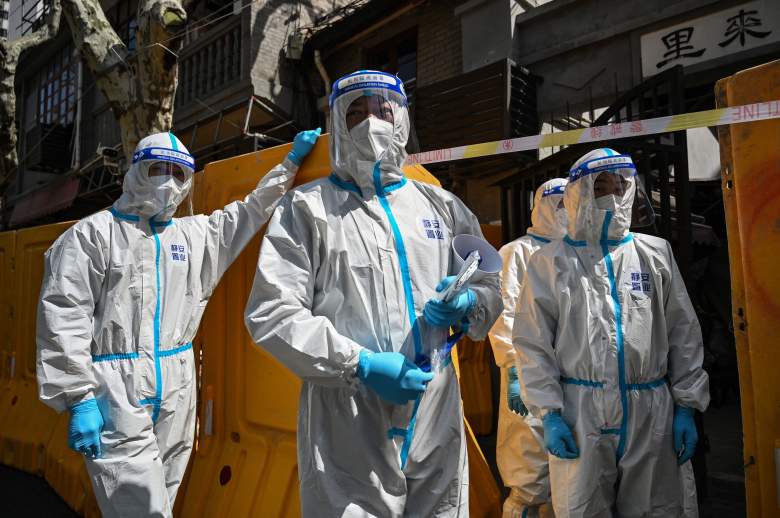 Trabajadores de una organización de servicio público con equipo de protección entregan verduras a los residentes de un barrio encerrado, en el distrito de Jing'an, en Shanghái, el 29 de marzo de 2022.